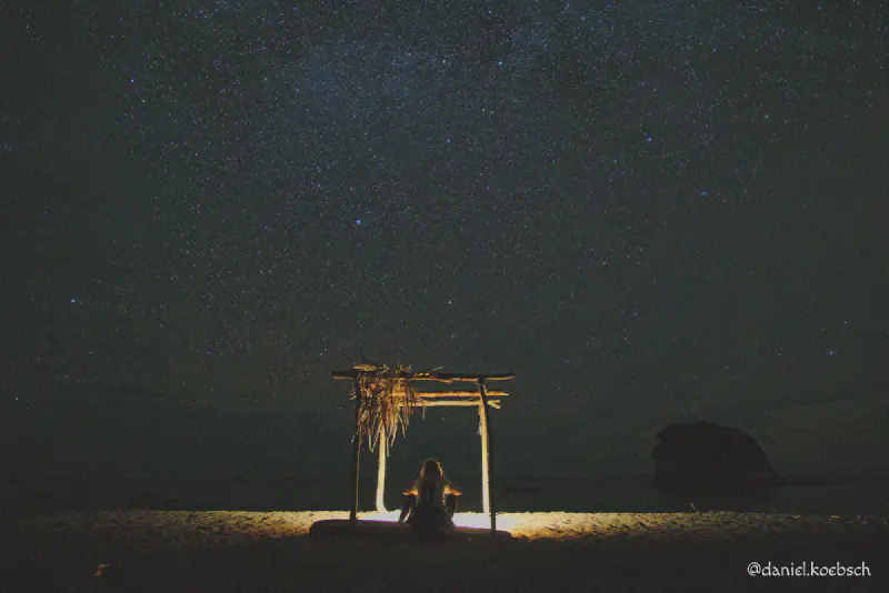 Silhouette eines Mädchens am Strand unter einem Sternenhimmel