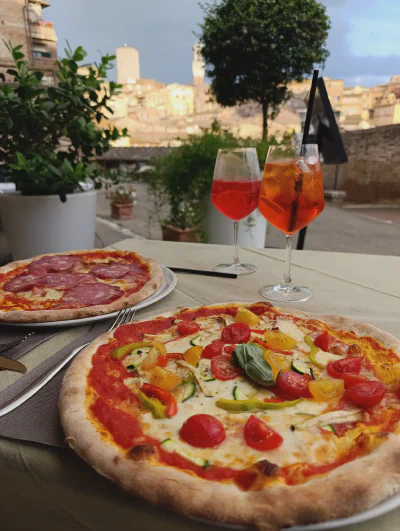 Das Abendessen mit Pizza und Aperol Spritz, genossen in einem Restaurant in der Via Camporegio mit Blick auf die Basilica di San Domenico.